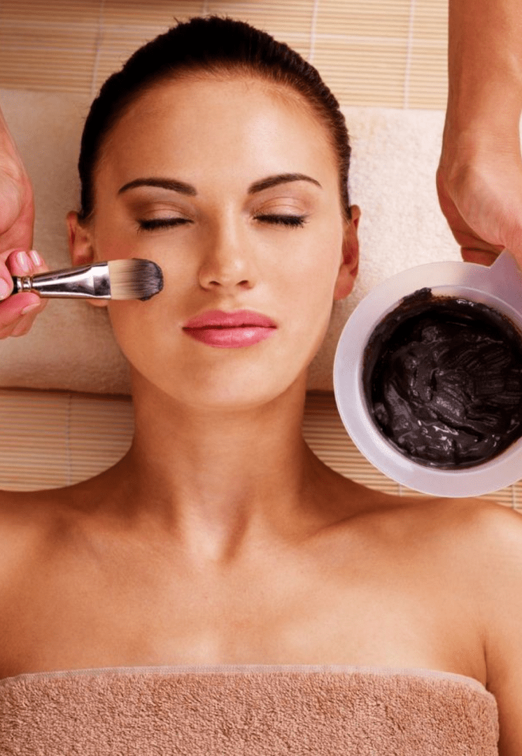 A woman getting her face washed with clay