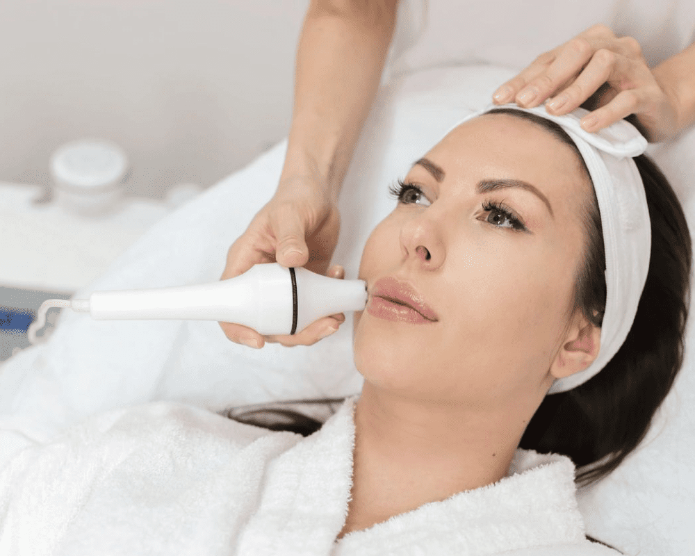 A woman getting her face cleaned by an esthetician.