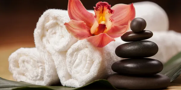 A close up of towels and stones with an orchid