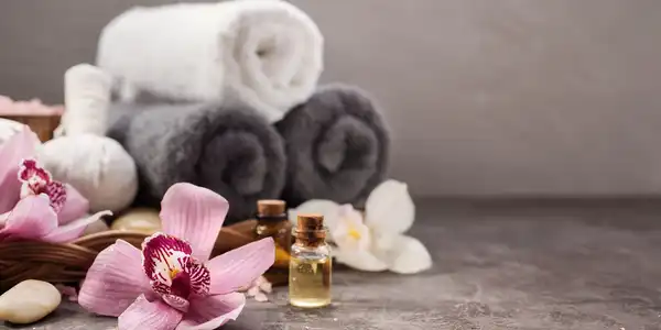 A close up of towels and flowers with an oil bottle