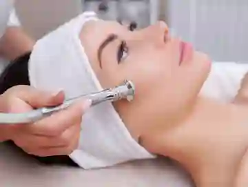 A woman getting her face cleaned with an electric device.