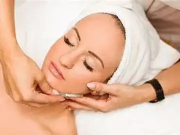 A woman getting her face washed with a towel.