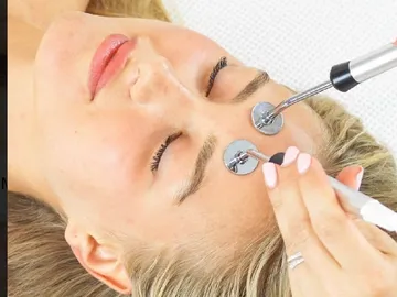 A woman getting her face shaped with an electric device.