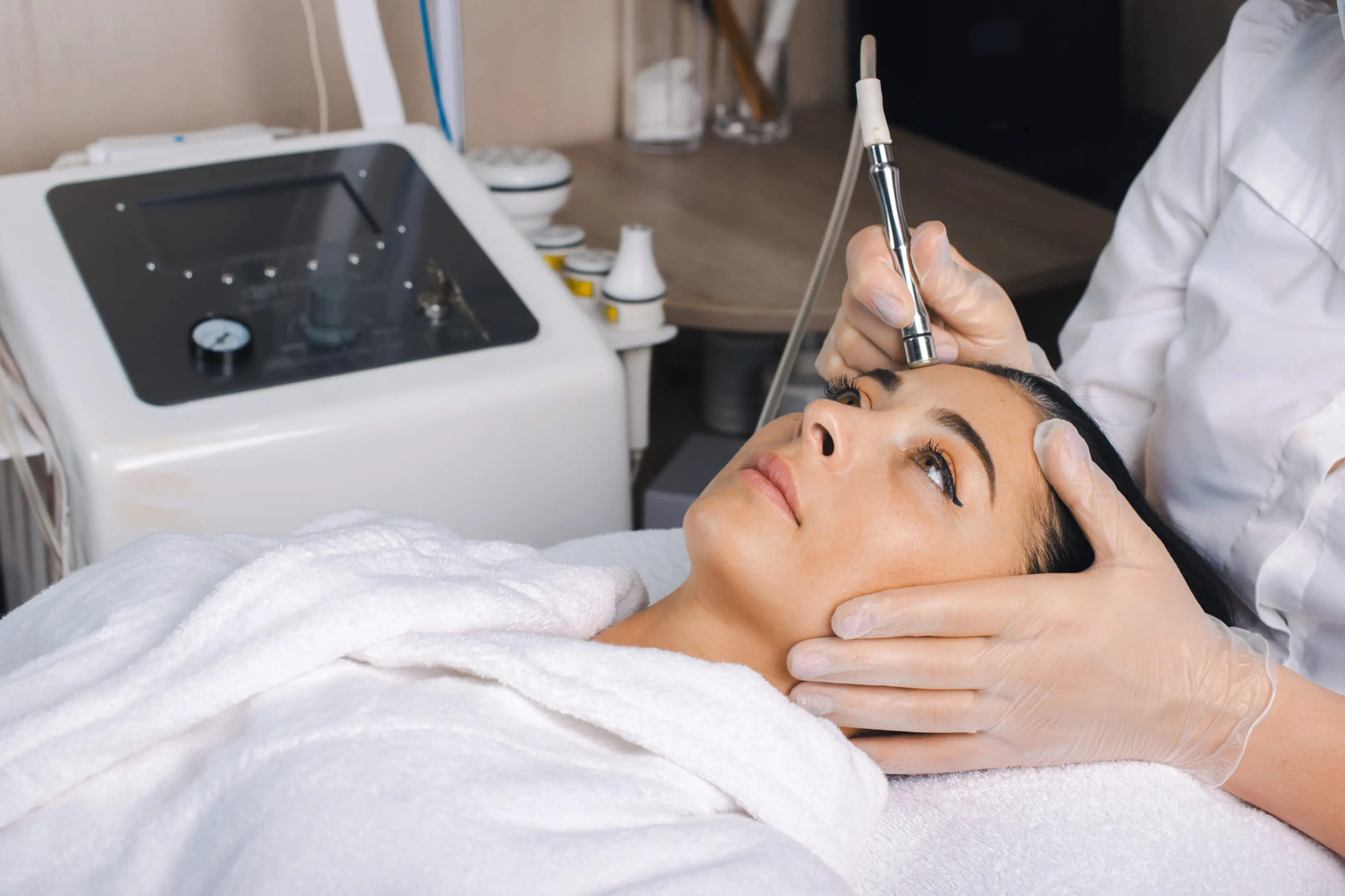 Side view of woman receiving microdermabrasion therapy on forehead at beauty spa. Rejuvenation treatment. Beauty face. Cosmetology beauty procedure.